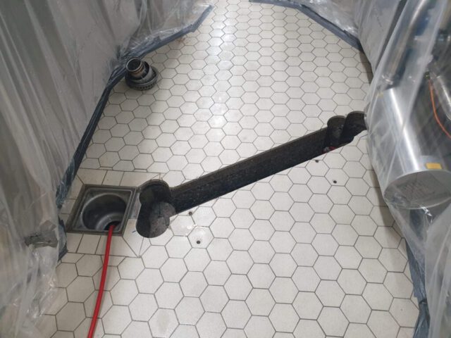 Kernbohrständer mit Bohrungen auf gefliestem Industrieboden mit Abdeckfolie Kernbohrständer mit Bohrungen auf gefliestem Industrieboden mit Abdeckfolie