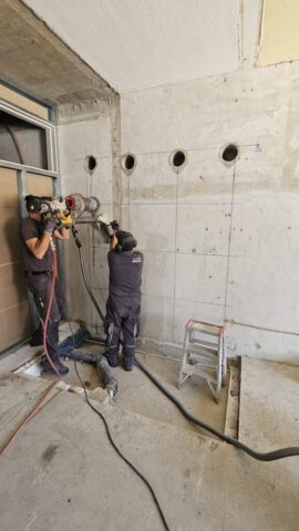 Zwei Mitarbeiter bei Kernbohrungen in Betonwand – Vorbereitung Wanddurchbruch Zwei Mitarbeiter bei Kernbohrungen in Betonwand – Vorbereitung Wanddurchbruch