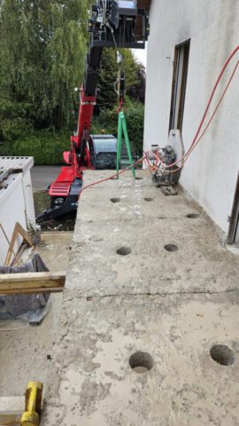 Balkonentfernung: Mehrere Kernbohrungen in Balkon Betonplatte neben Wohnhaus mit Minibagger