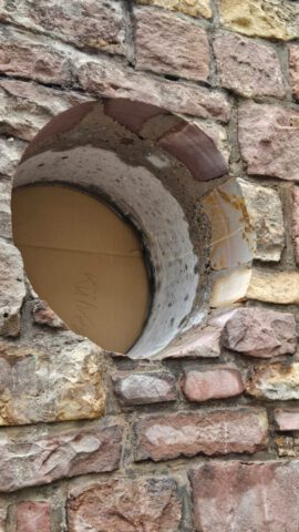 Kernbohrung durch Natursteinmauer für Leitungsdurchführung
