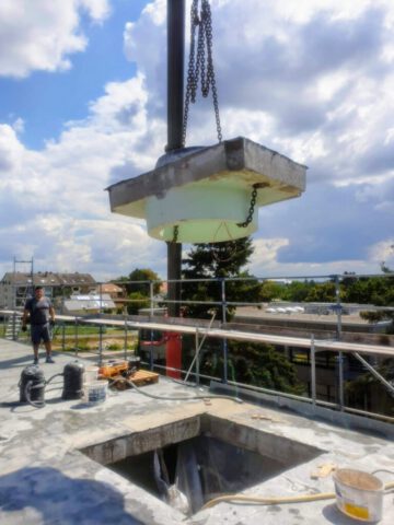 Betonblock wird per Kran von Flachdach gehoben nach Kernbohrung