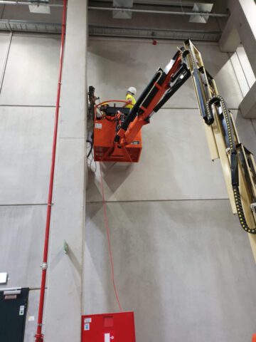 Kernbohrung in großer Höhe an Betonwand mit Gelenkteleskopbühne in Industriehalle